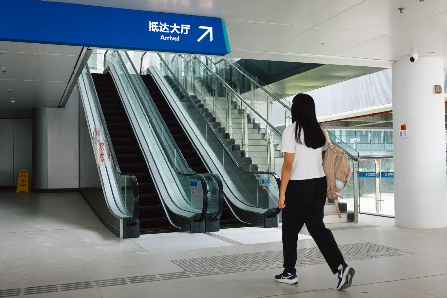  A ferry passenger heads towards a set of escalators heading up towards Arrivals. 