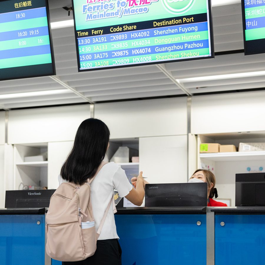 A passenger stands at a ticketing counter to get a ferry ticket.