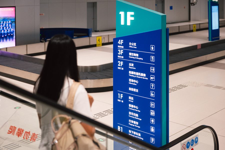 A passenger looks at the directory as they take an escalator down to the luggage belt.