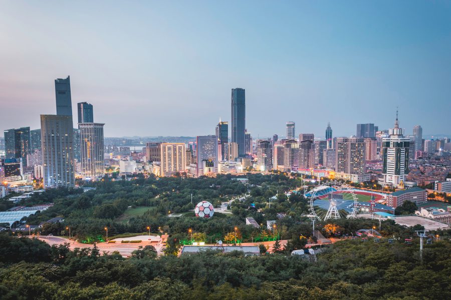 An aerial view of Zhongshan shows skyscrapers surrounding a deep green forest at dusk.