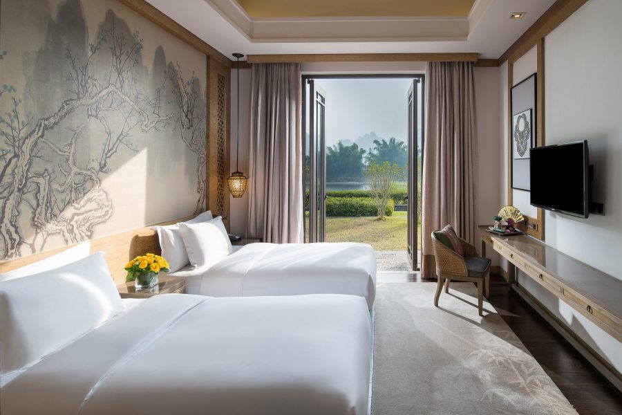 A twin room at Banyan Tree Yangshuo with a garden through the open doors. 