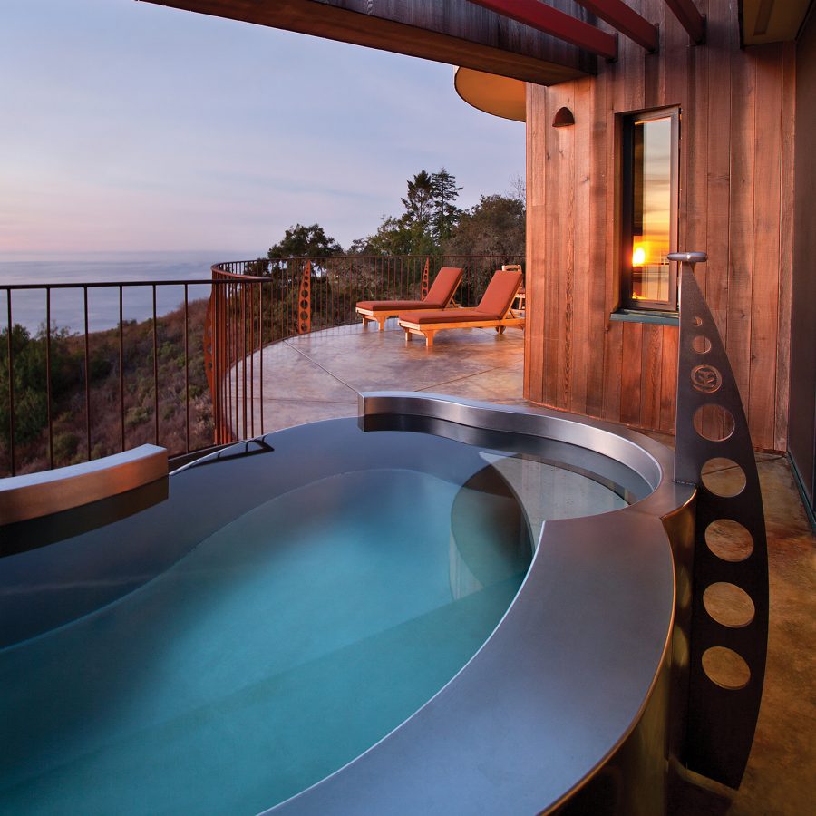 A hot tub and two lounge chairs on a deck at Post Ranch Inn.