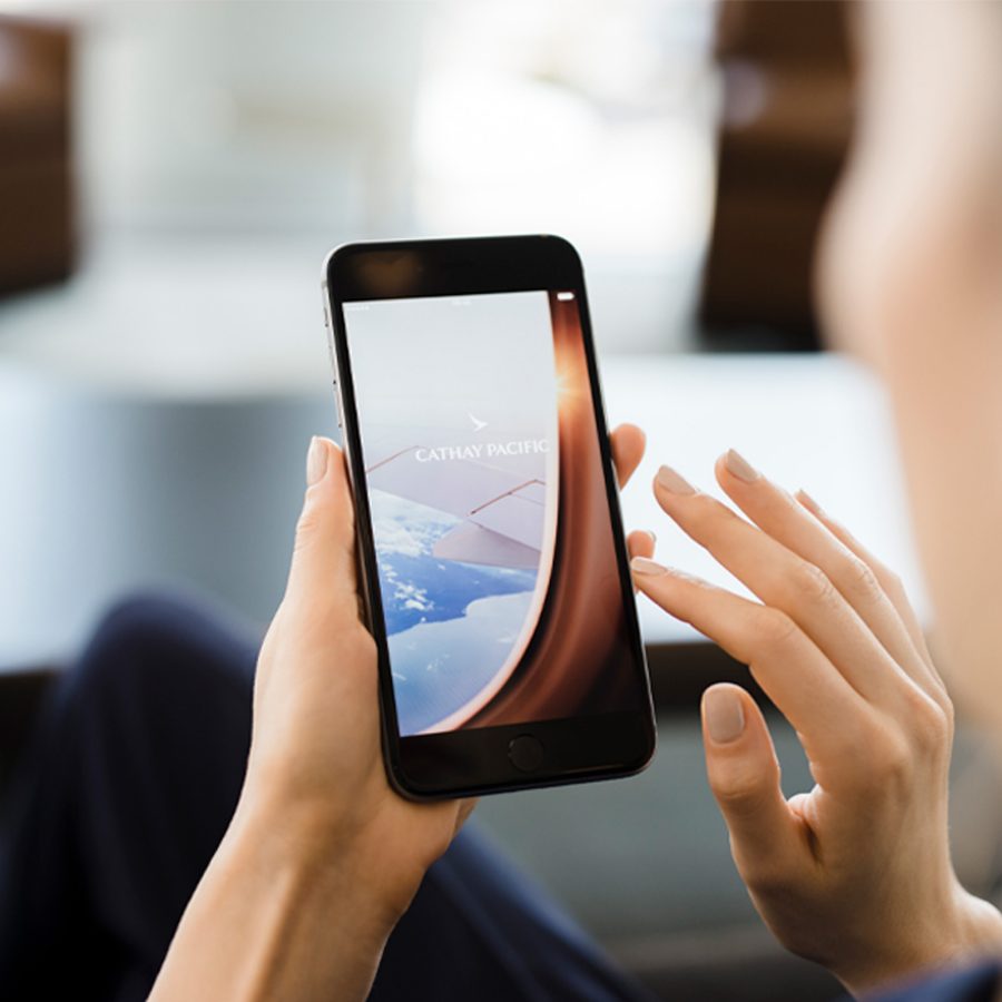 Over the shoulder shot of a man logging into the Cathay Pacific app on his iPhone.