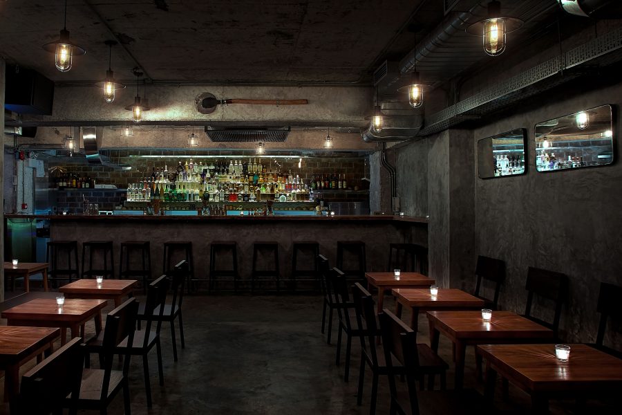 An interior view of COA in Hong Kong, featuring low lighting, low wooden tables and a cosy, intimate space