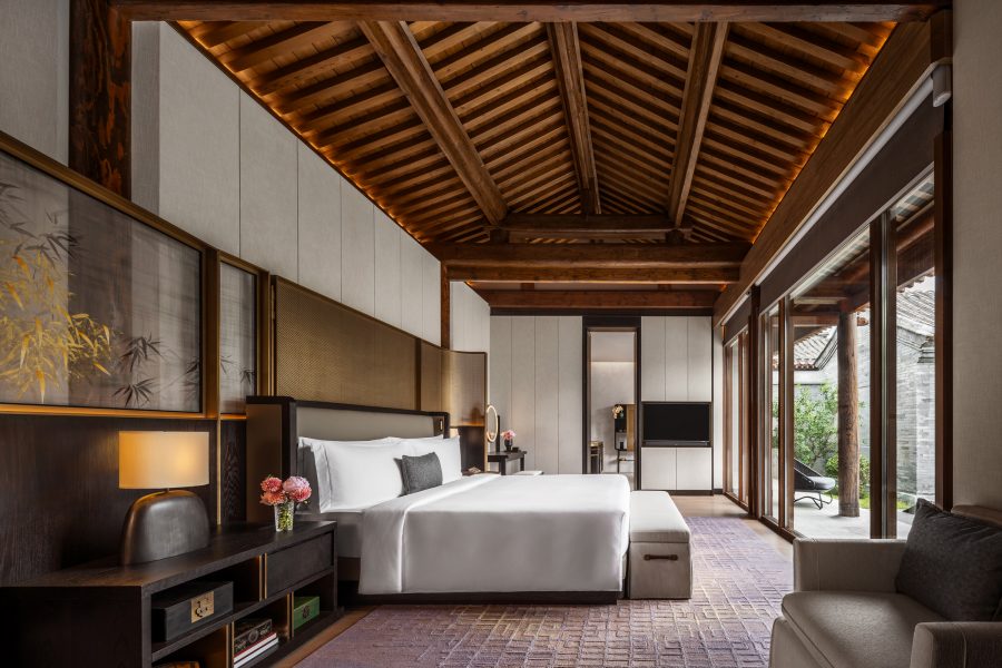 A bedroom in the Mandarin Oriental Qianmen in Beijing with an exposed beam roof and sophisticated furniture