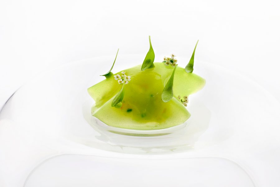 A closeup of a Normandy brown crab, Nashi pear, avocado & wasabi oil, served in a clear bowl at Odette in Singapore