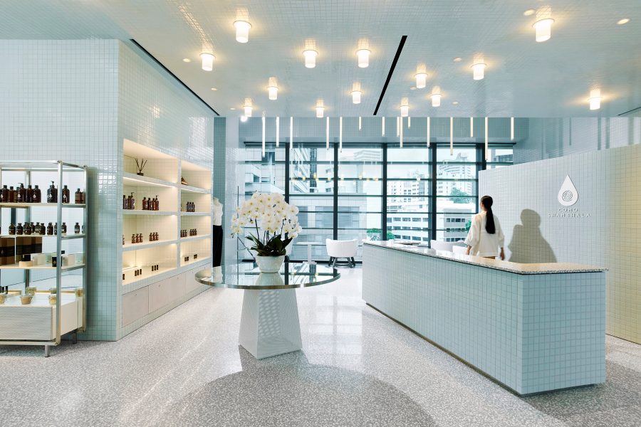 A woman standing behind a reception desk at the COMO Shambhala, Singapore.