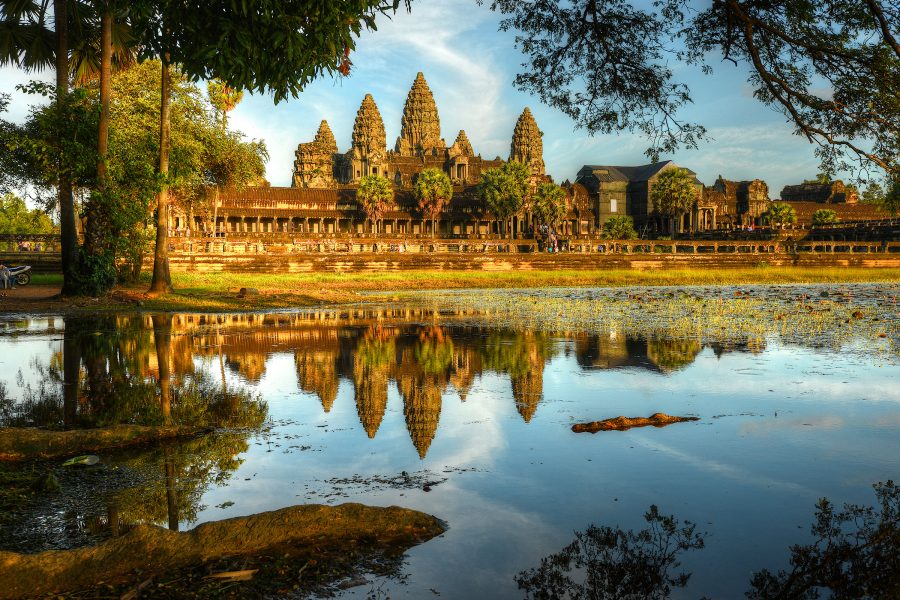 Angkor Wat surrounded by trees, with a body of water in front
