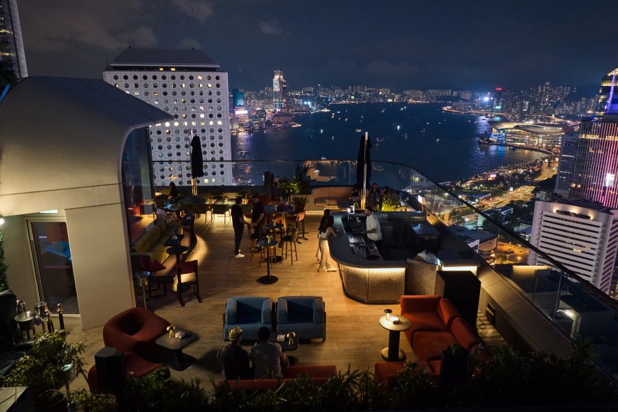 Cardinal Point’s outdoor seating area overlooks the glowing Victoria Harbour at night.