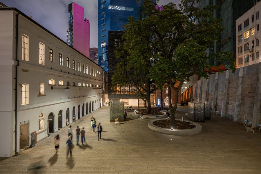 People mill about in the courtyard of Tai Kwun in Central at night.