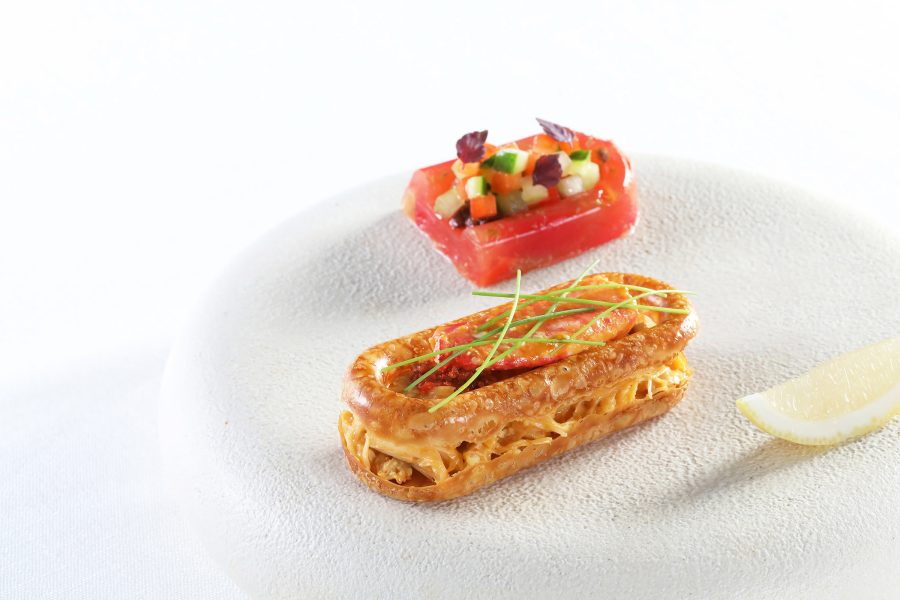 A small plate features a pastry next to a slice of tomato holding up some salsa, served at Ta Vie.