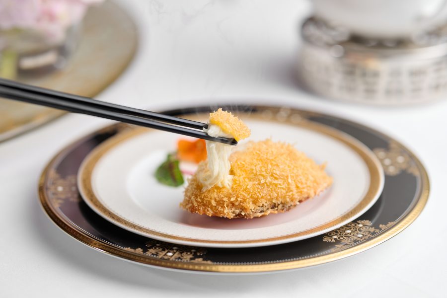 Chopsticks pick up a piece of a deep fried stuffed crab shell, available at T’ang Court.