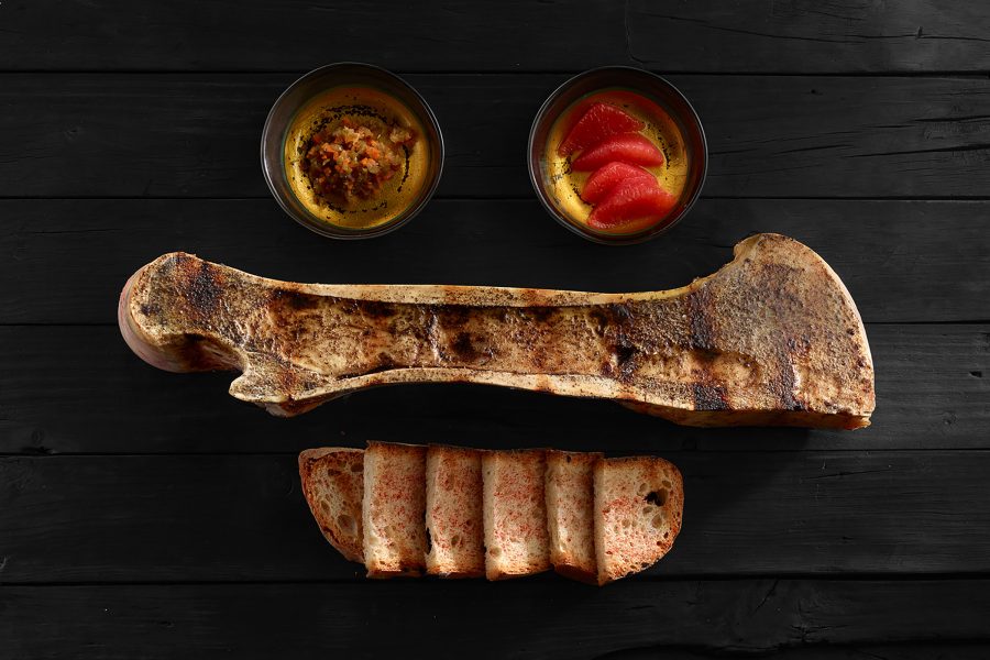 Topshot of a bone marrow dish at Bodega El Capricho served alongside bread and two small bowls
