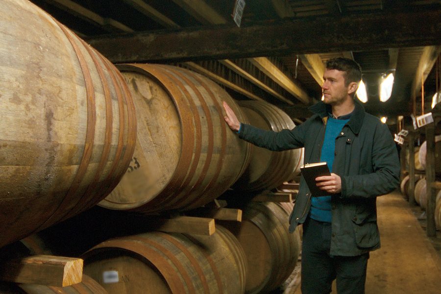 Euan Kennedy passing a hand over a barrel at The Macallan Distillery.