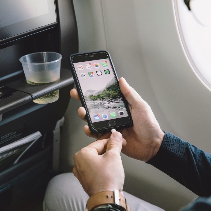 Interior shot of a cabin with someone using the USB power socket in the seat in front to charge their smartphone. 
