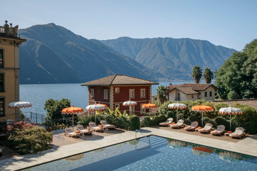 Exterior view of the outdoor swimming pool at the Grand Hotel Tremezzo in Lake Como. The lake and mountains are in the background. 
