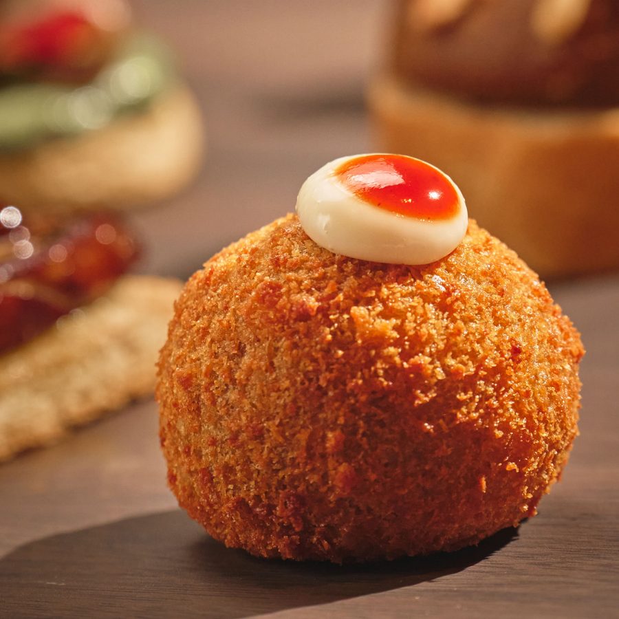 A fried ball with a drop of sauce on top is one of the bites available for order at Pintxos by Bàrbar. 