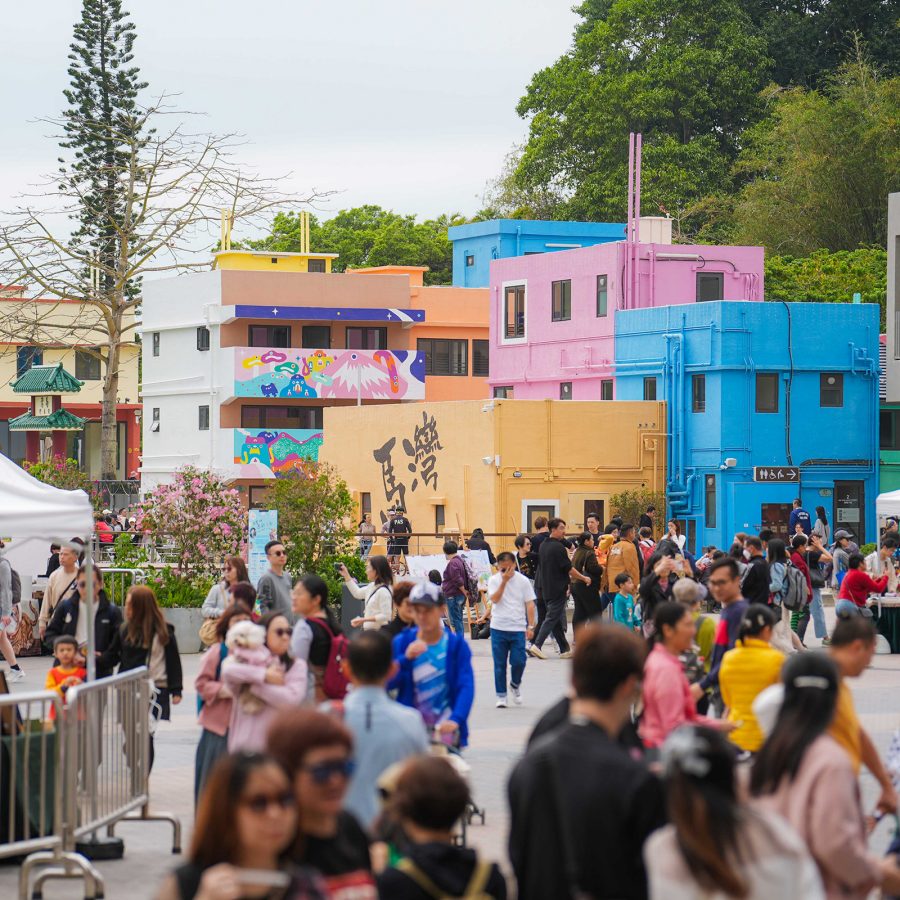 Crowds pass by Ma Wan 1868’s colourful buildings in Hong Kong.  