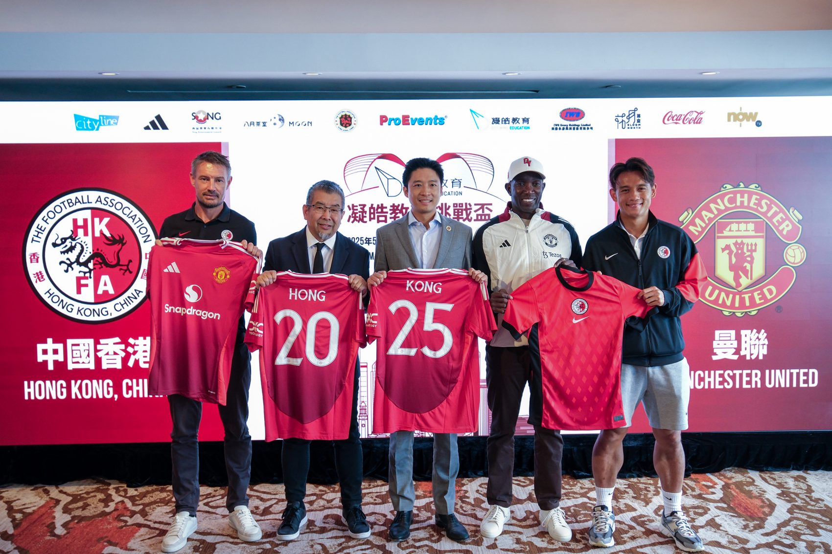 Former football player Dwight Yorke, members of the Hong Kong football association and more hold up Manchester United football shirts which read Hong Kong.
