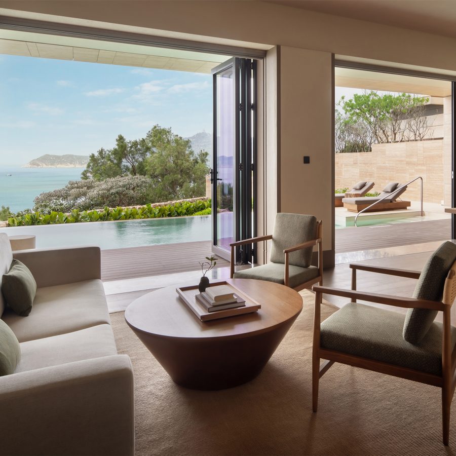  The interior of a guest room at Alila Dong’Ao Island Zhuhai is filled with comfy furniture and looks out at an outdoor infinity pool and the coast. 