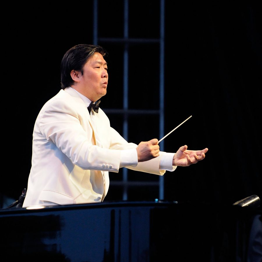 Long Yu, conductor of Guangzhou Symphony Orchestra, stands on stage conducting.