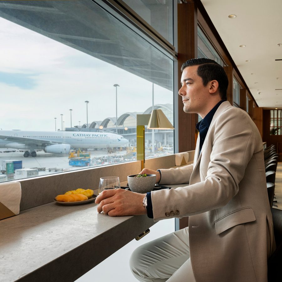 A man sits at a bar table facing the runway at The Bridge, a Cathay Pacific lounge that has recently opened. 