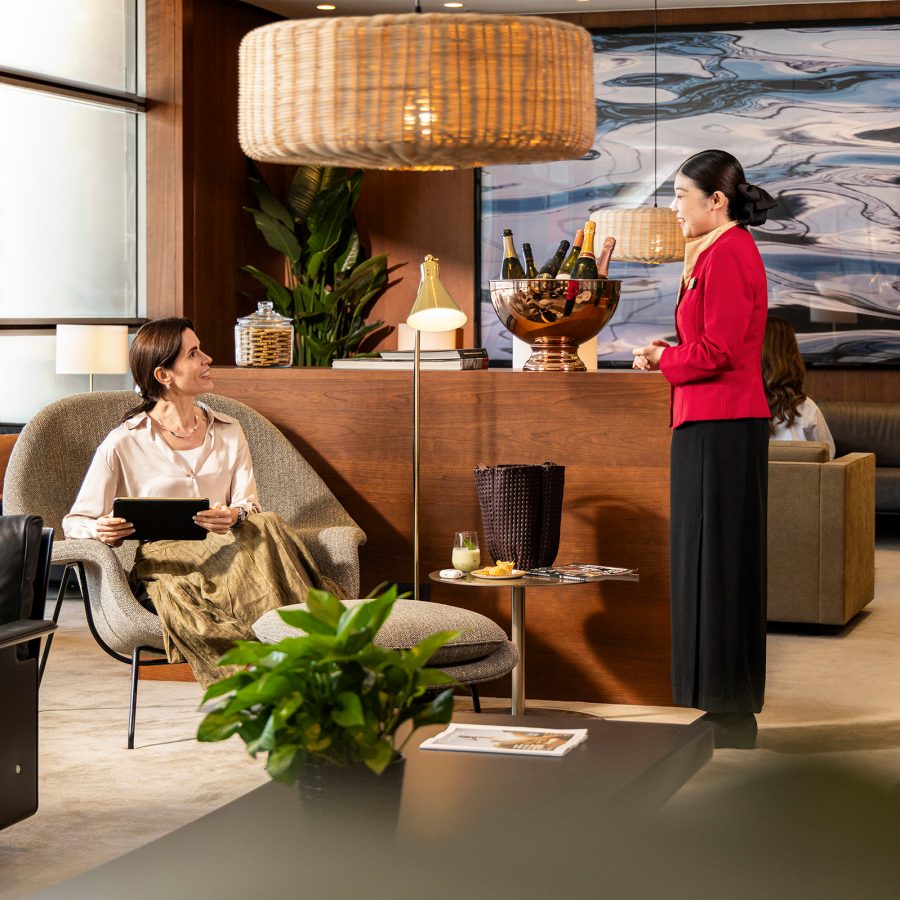 A Cathay Pacific staff member chats with a customer sitting on a pelican chair in a lounging area inside The Bridge.