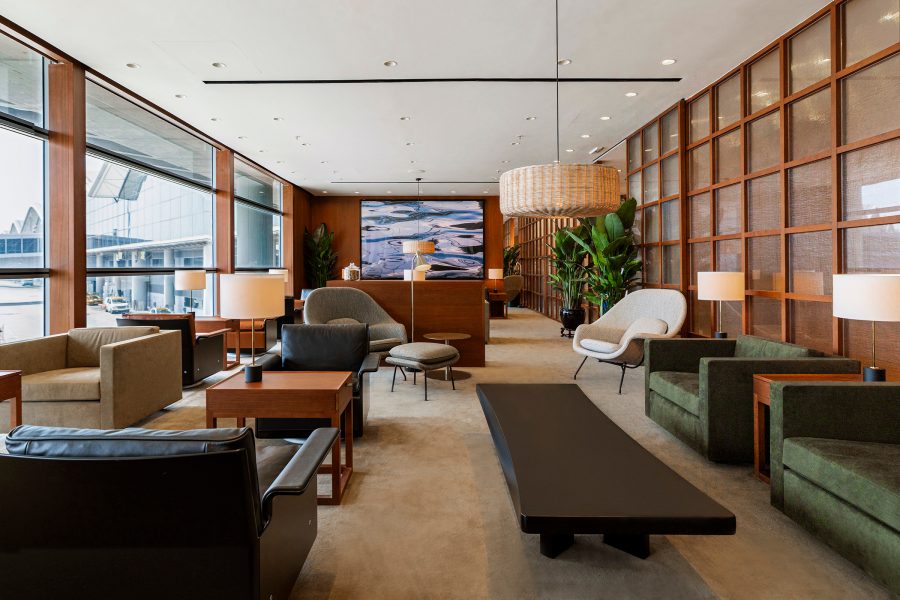 A private seating area with sofas, chairs and low tables, plus a view of the Hong Kong airport runway, at The Bridge. 