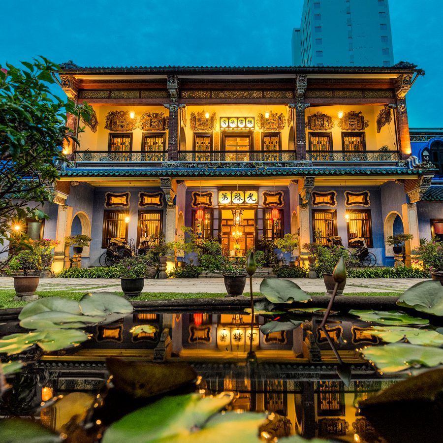 The exterior of The Blue Mansion and outdoor pond in George Town at dusk.