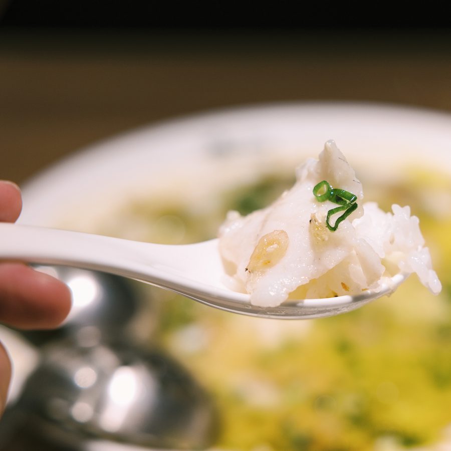 A closeup of a spoon filled with spicy and sour fish broth with rice served at Tai Er in Sha Tin, Hong Kong.