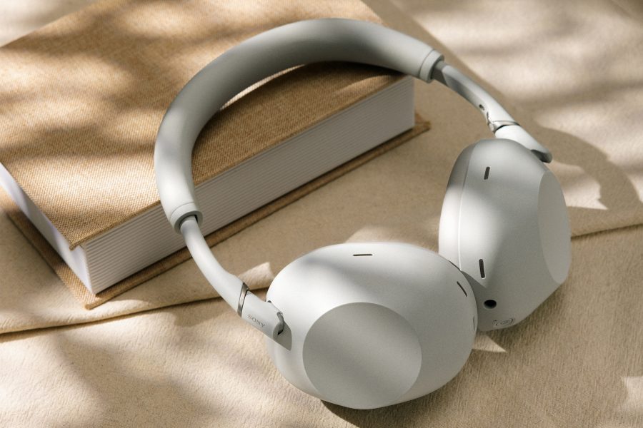 A pair of Sony WH-1000XM6 headphones in platinum silver placed on top of a book.