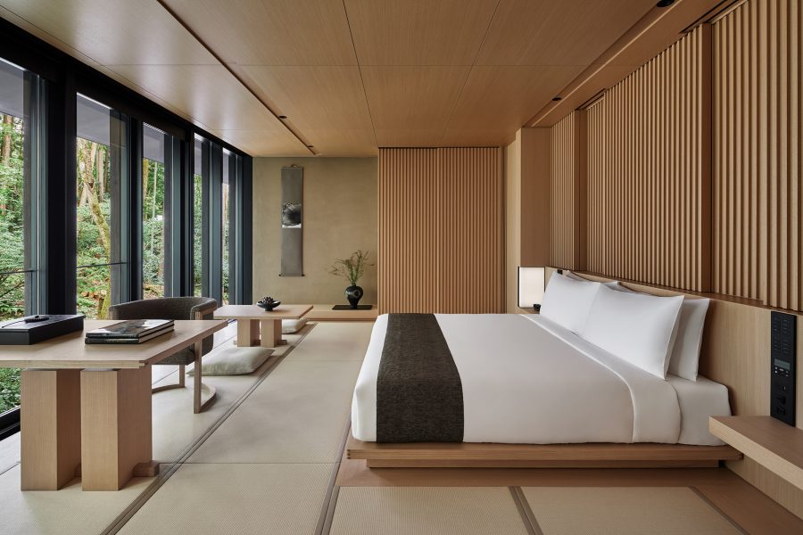 A hotel bedroom with wooden interiors and a garden view.