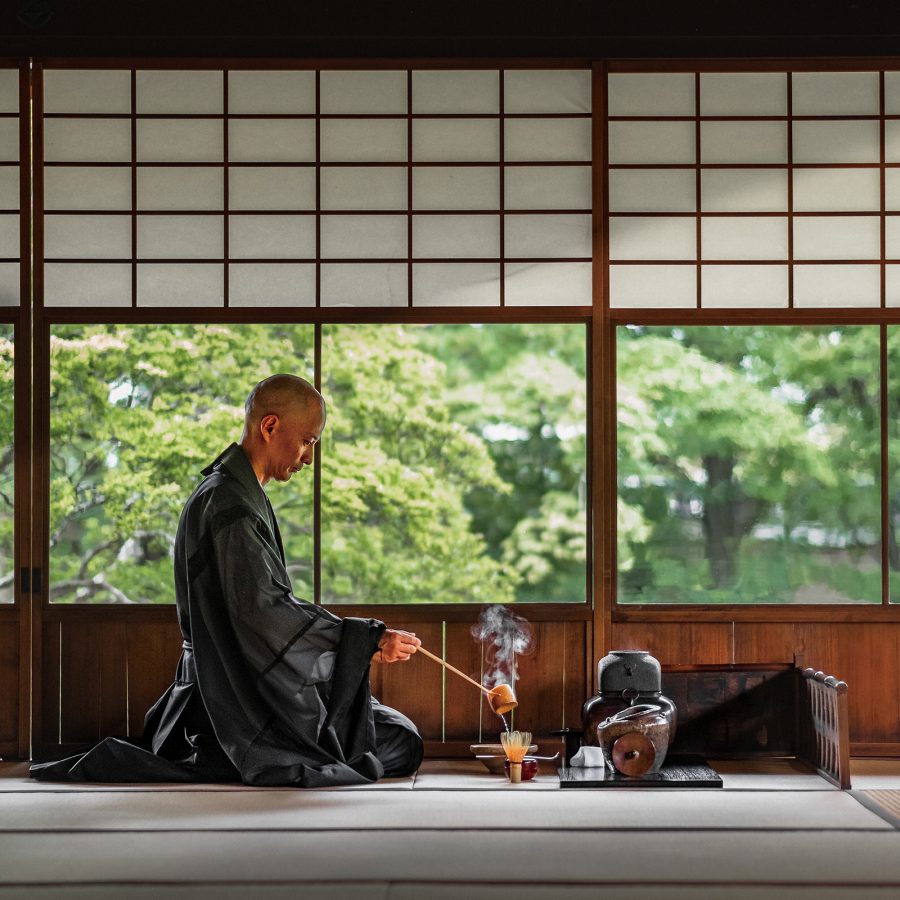 A monk kneeling on the floor preparing hot tea.