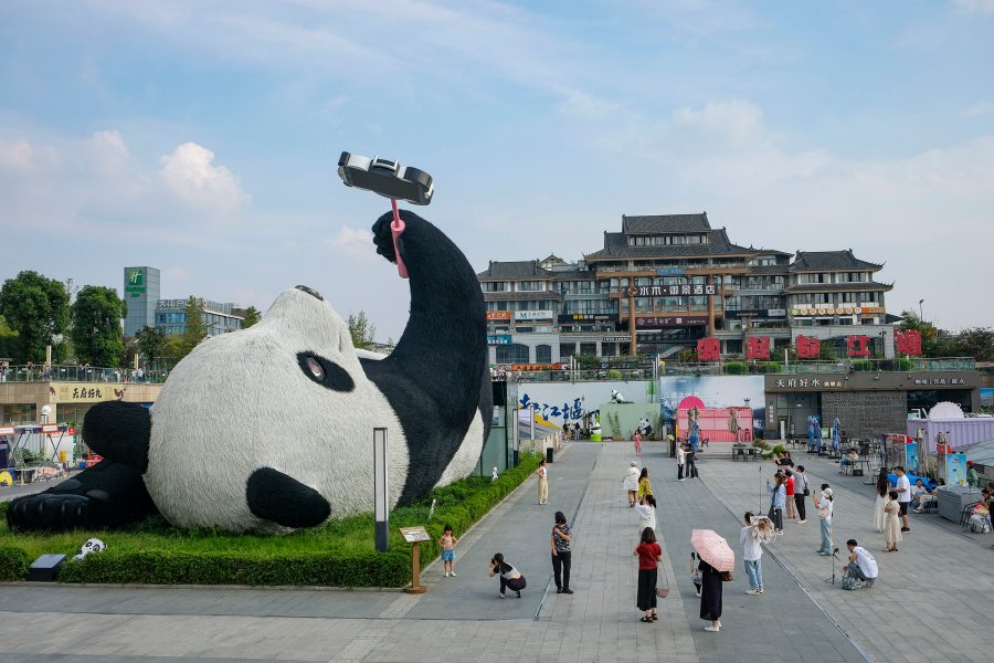 Exterior view of the Chengdu Research Base of Giant Panda Breeding, with visitors looking at a sculpture of a giant panda, with buildings in the background.