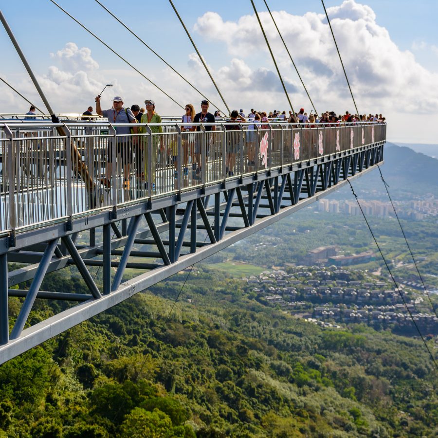 Exterior view of visitors walking along a bridge at Yanoda Rain Forest Culture Tourist Zone. 
