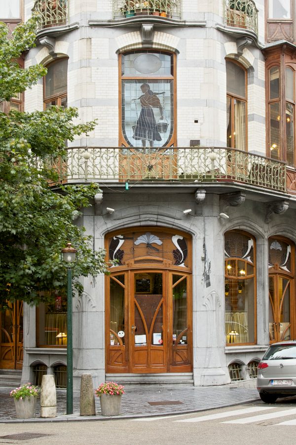 The exterior of a multi-storey building in Brussels shows a storefront on the ground floor. 