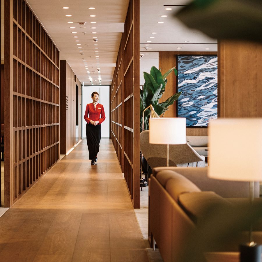 A flight attendant walks down a hallway lined with timber framed screens at The Bridge. 