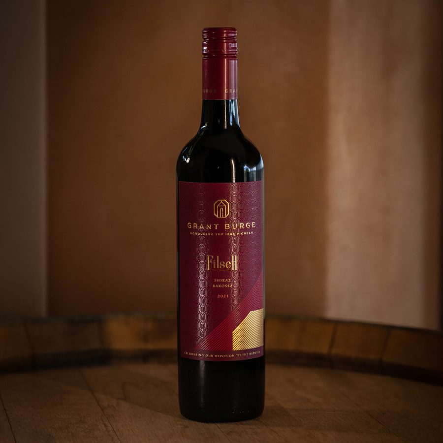 Closeup of a bottle of Grant Burge Filsell 2021 on top of a wooden barrel. 