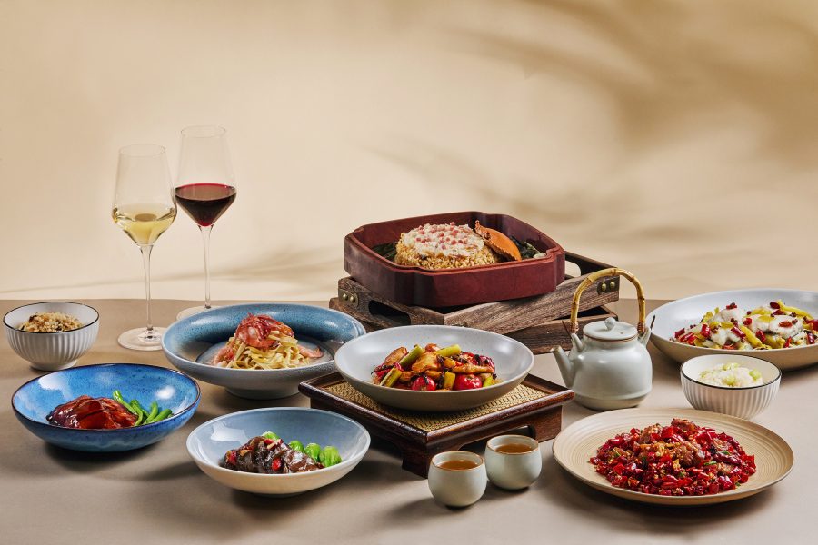 A table laden with two glasses of red and white wine, a teapot and two cups of tea, and dishes from Cathay Pacific’s Chinese Classics inflight menu.