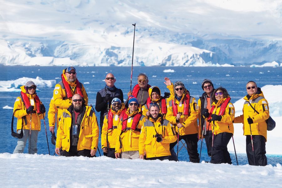 A group of LGBT+ travellers pose with glaciers in the background.