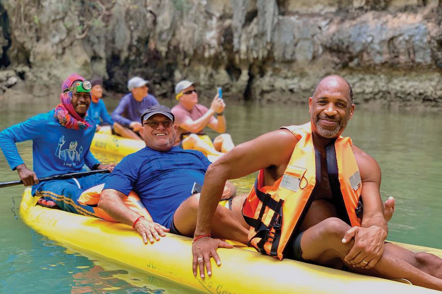 Two kayaks cruise through the water as men smile at for the camera