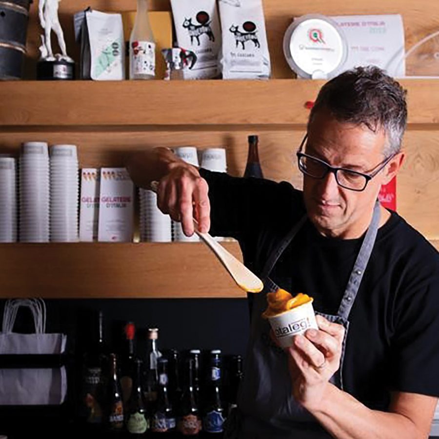   Man scoops gelato into a cup at Otaleg! in Rome.