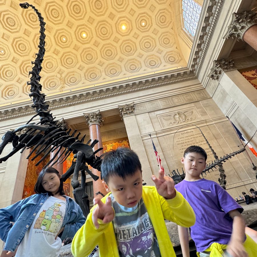 Juan’s three children pose in front of a dinosaur skeleton at a museum in New York.