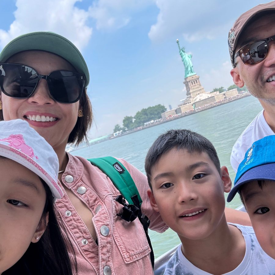 Juan, his wife and his three children smile with the Statue of Liberty in the background.