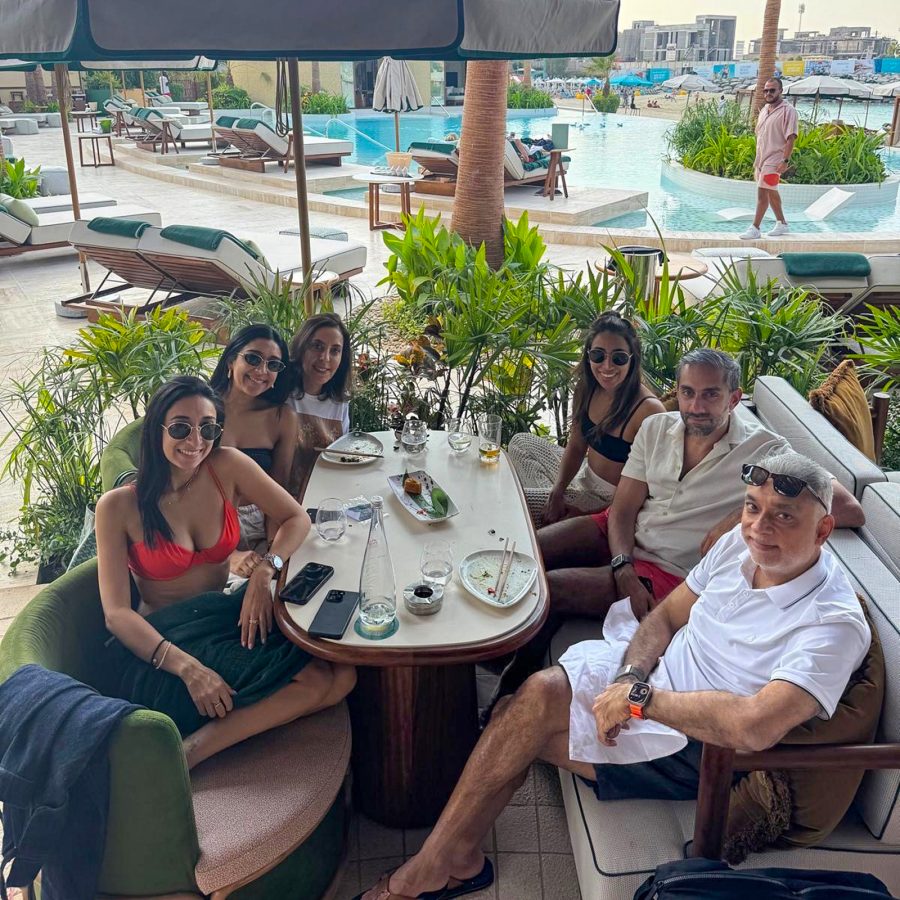 Vijay Daswani and his wife, three daughters and son-in-law sitting at a table in Dubai. A pool is in the background.