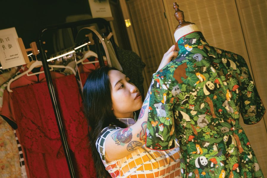 Chocolate Tsang adjusts the collar of a panda-themed cheongsam on a mannequin.