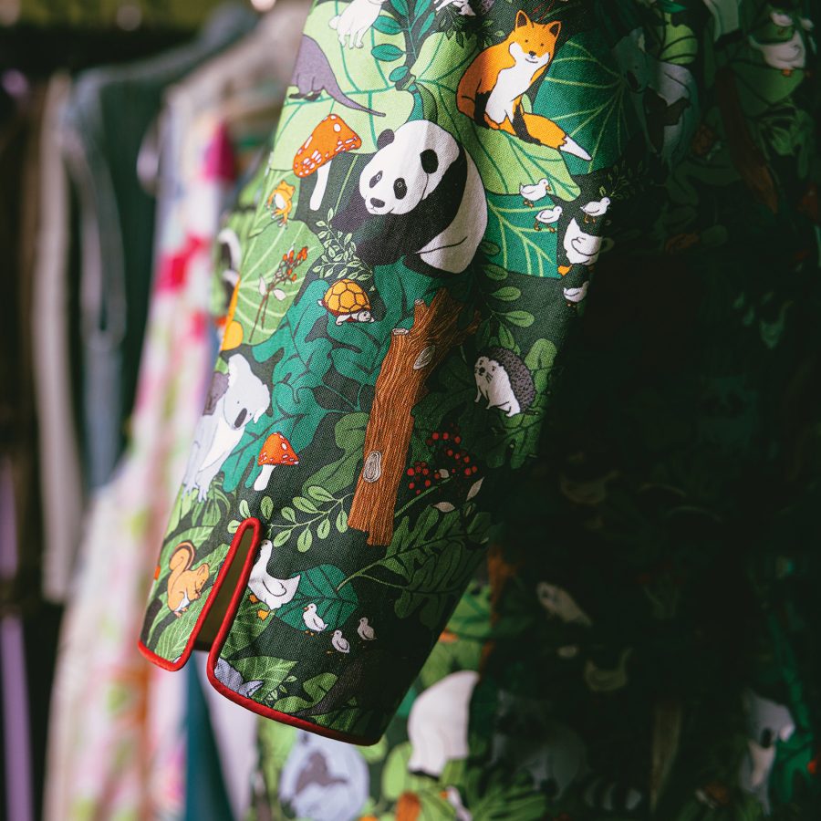 A close-up of a panda-themed cheongsam at Stand Tall D shows a panda, a red fox and a porcupine among other animals interacting with plants.