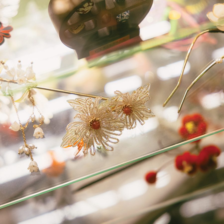 Chinese-style hair pins rest atop a glass shelf reflecting light from the ceiling.