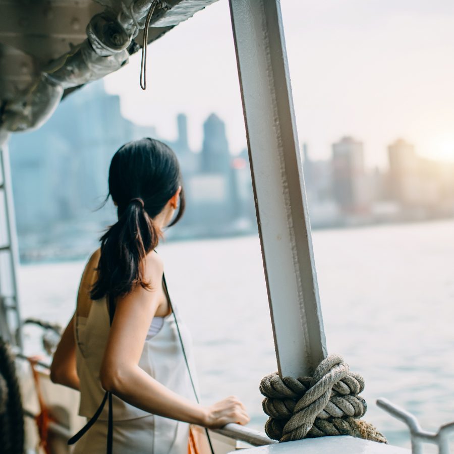 A woman looks out a window on the Star Ferry at Hong Kong’s skyscrapers by the water. 