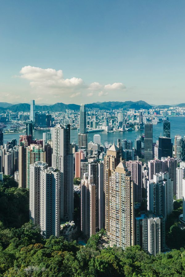 A view of Hong Kong from the Victoria Peak shows skyscrapers rising toward a blue sky.